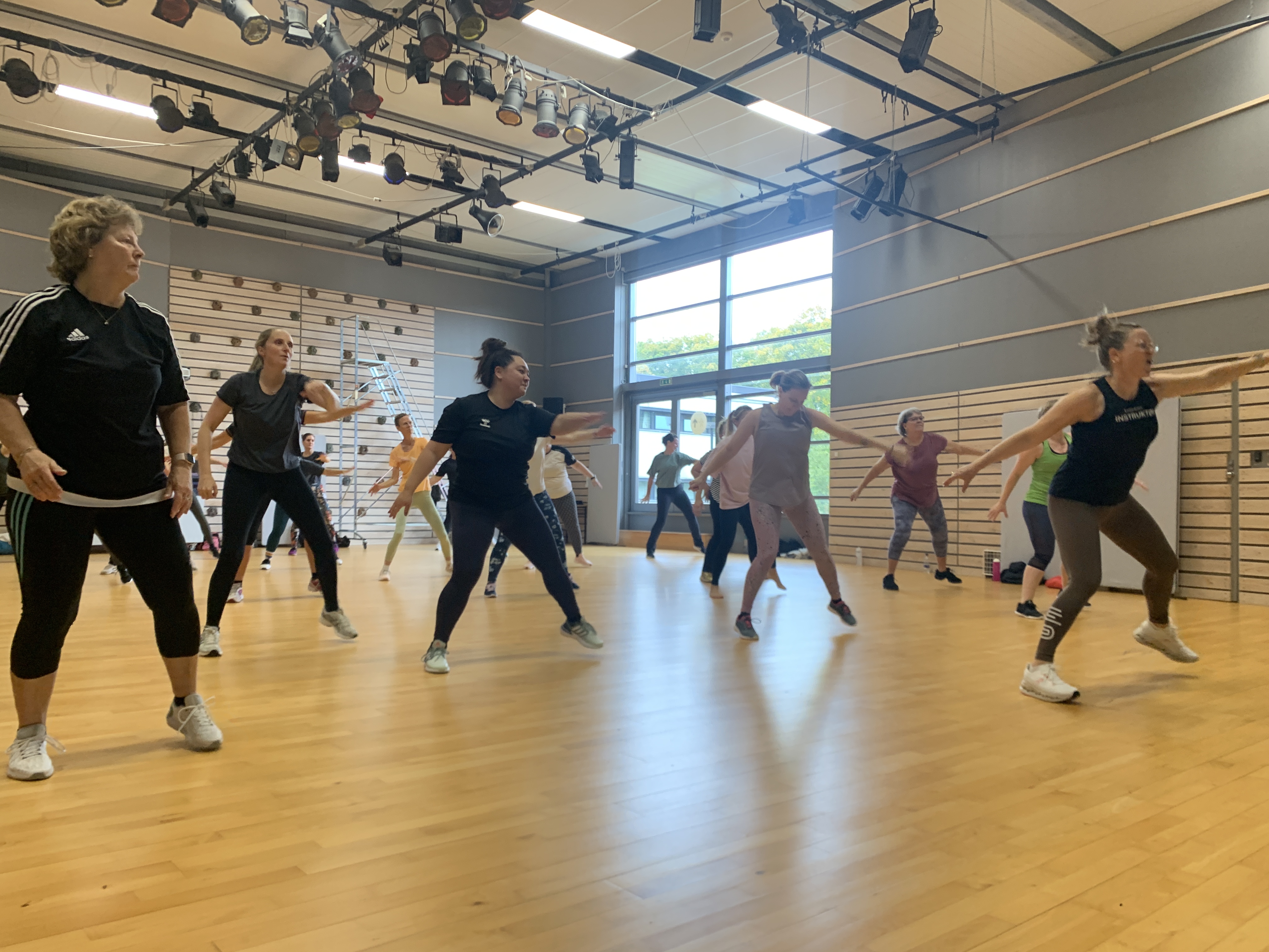 People exercising together in a group fitness class inside a gym studio.