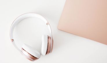 Billedet viser høretelefoner og en kant af en computer