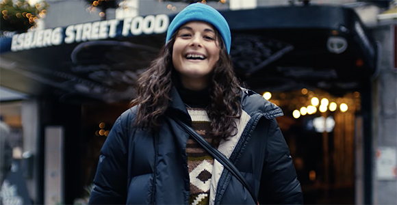 Young woman smiling - Eloïse from the video. She is standing in front of Esbjerg Street Food. 