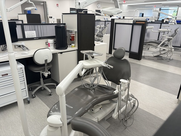 Moderne tandlægeklinik med en tom tandlægestol, avanceret udstyr og afskærmede behandlingsstationer. Klinikken er ren og professionelt indrettet med fokus på hygiejne og komfort, ideel til tandbehandling og patientpleje.