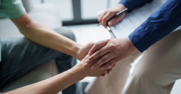 Adult with pen and paper puts hand on teenagers hand