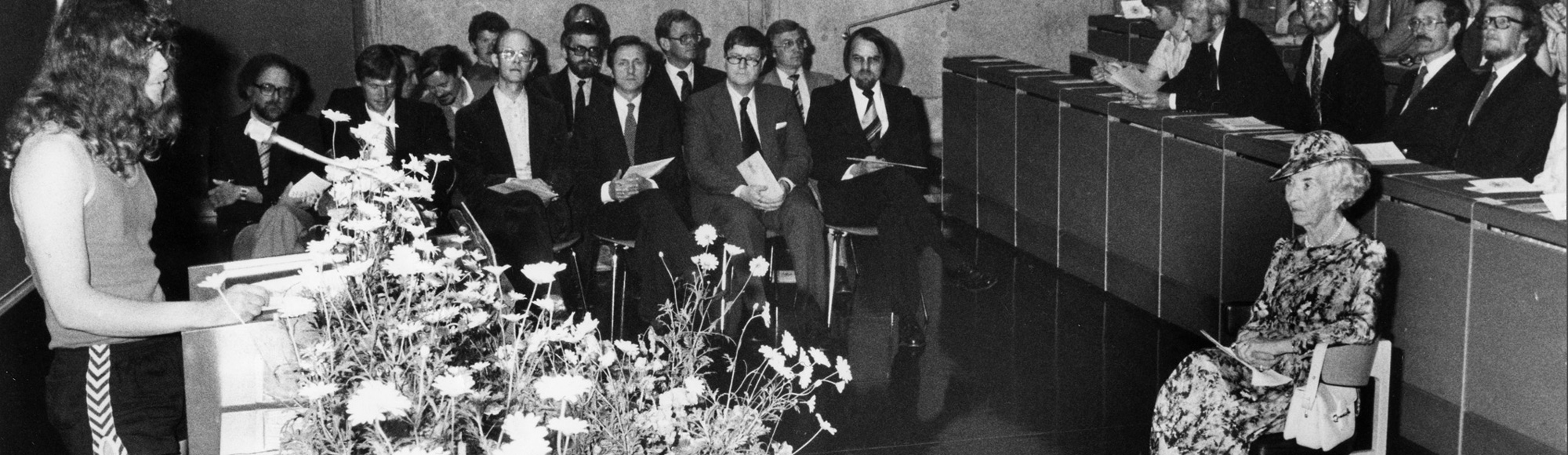 Billede af Roald Andersens tale fra årsfesten i 1982, hvor han står foran blandt andre Dronning Ingrid iført ærmeløs JBS-undertrøje, Hummelshorts og Kalsøsko