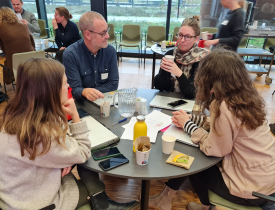 Deltagere fra Projekt- og porteføljenetværket sidder ved et bord og har en samtale. 
