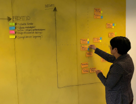 En kvinde står og sætter post-its på en gul tavle. 