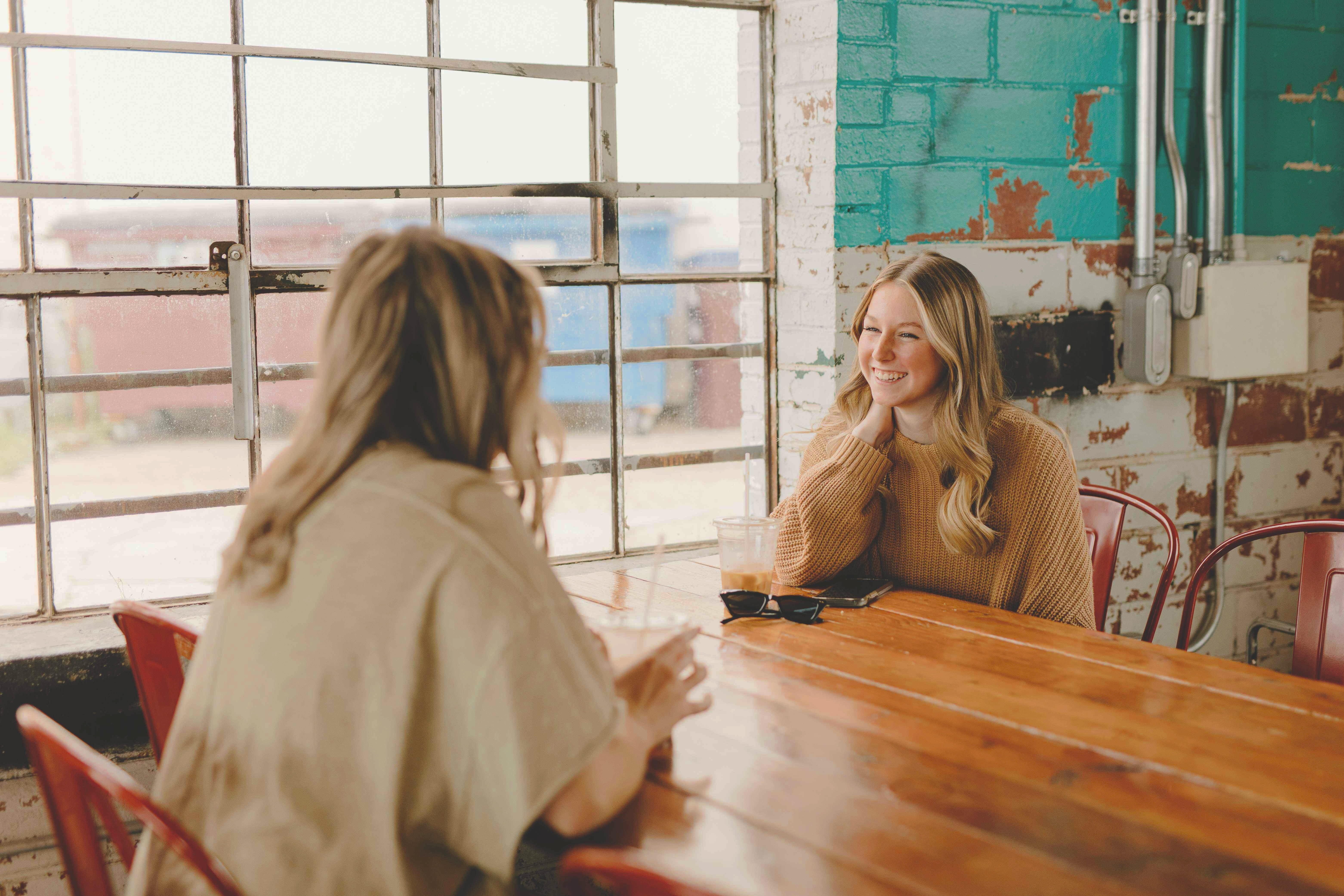 To unge kvinder sidder ved et bord og har en samtale.